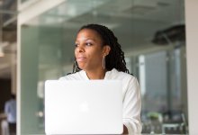 A professional Black woman looks out the window with a reflective expression